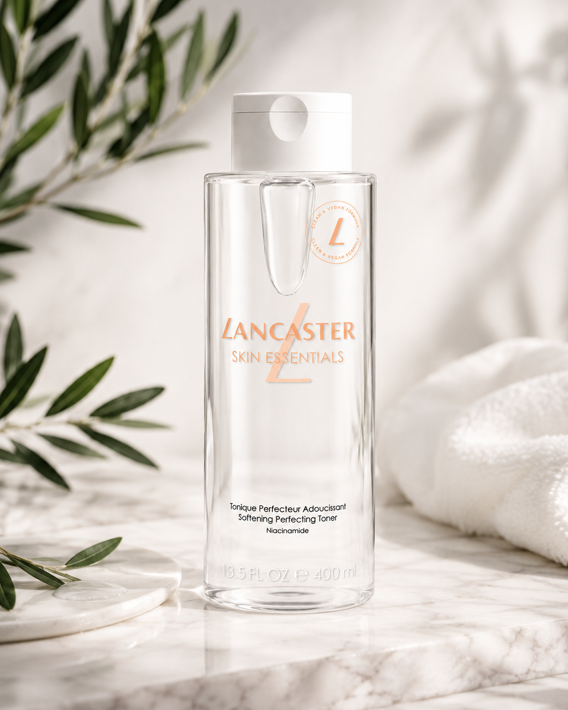 Lancaster Skin Essentials Softening Perfecting Toner elegantly displayed on a polished white marble vanity in warm natural daylight. The fresh skincare setting features delicate olive branches casting soft organic shadows, plush folded white spa towels, a round marble tray with a clear water droplet accent, and a bright airy spa atmosphere inspired by clean beauty.